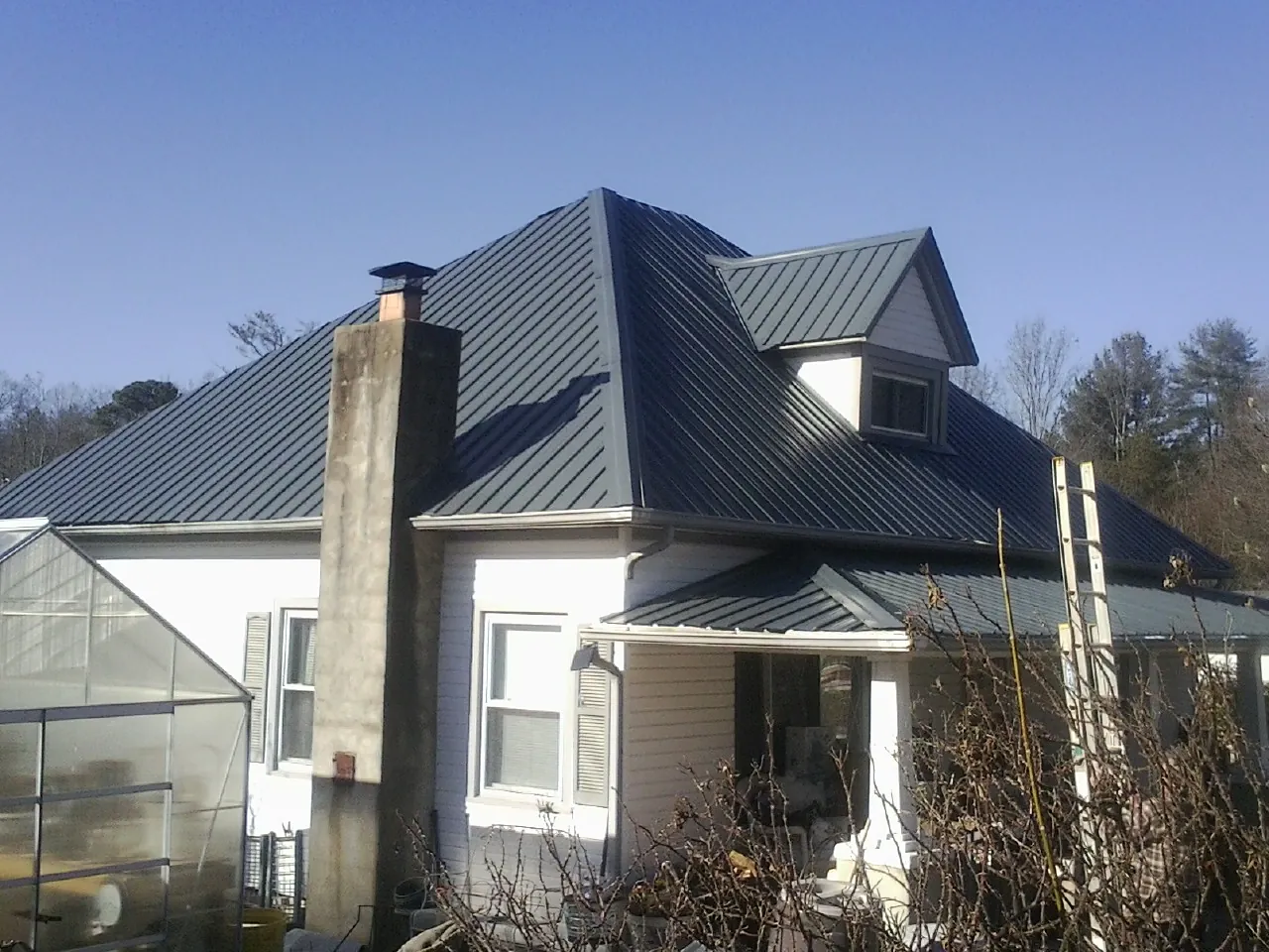 Dark blue standing seam metal roof on a white farmhouse with dormer — Slate & Tile Roof Repair by Roofing Brothers in Dubois