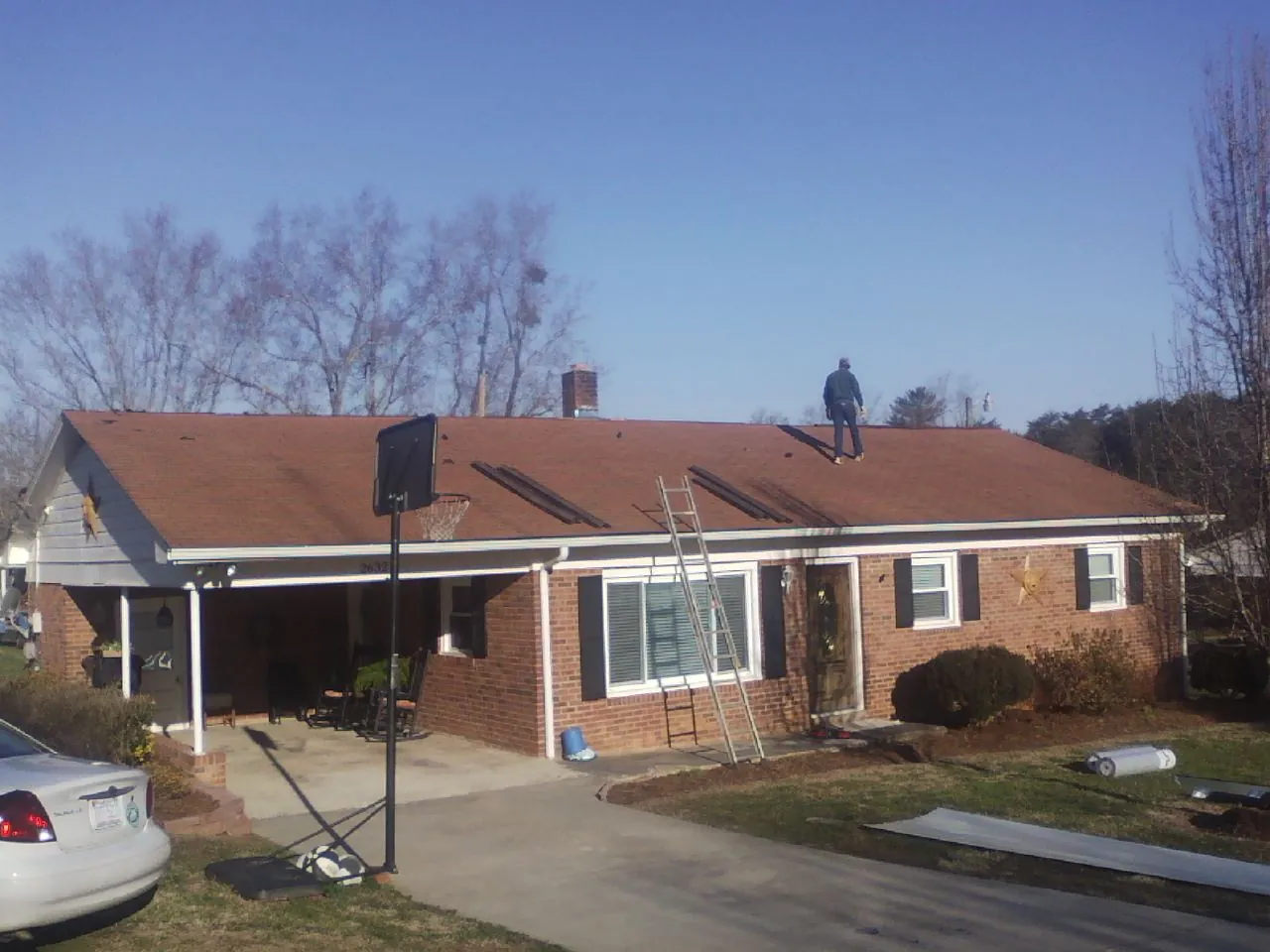 Roofer stripping a shingle roof on a brick ranch before metal panels in Dubois