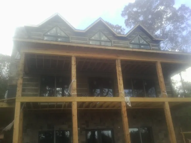 Dormers and porch framing on a large log home under construction — Roof Coating work by our crew in Dubois