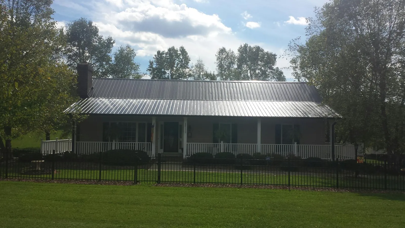 Gray metal roof on a brick ranch with a full width front porch — Gutter Guard Installation work by our crew in Dubois