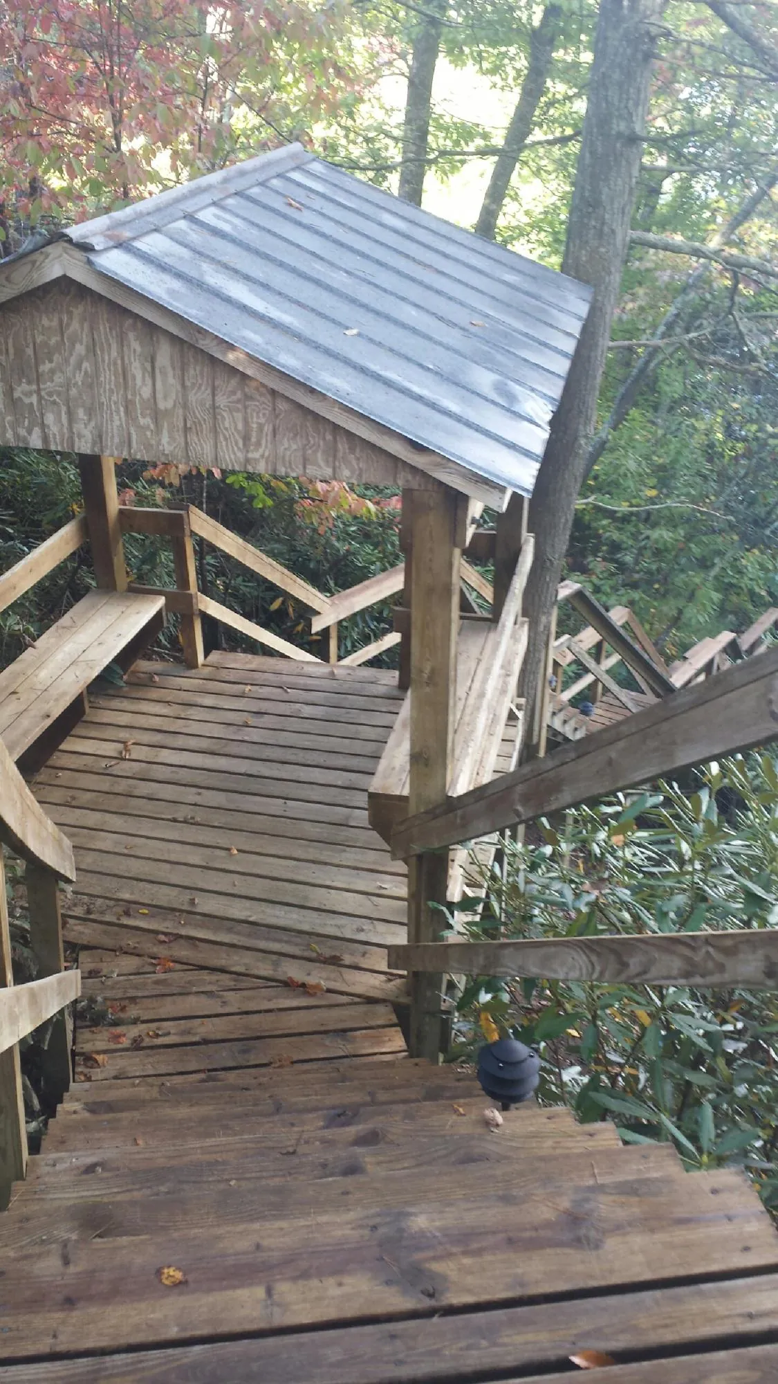 Metal roofed shelter over wooden steps on a wooded walkway — Skylight Repair & Installation work by our crew in Dubois