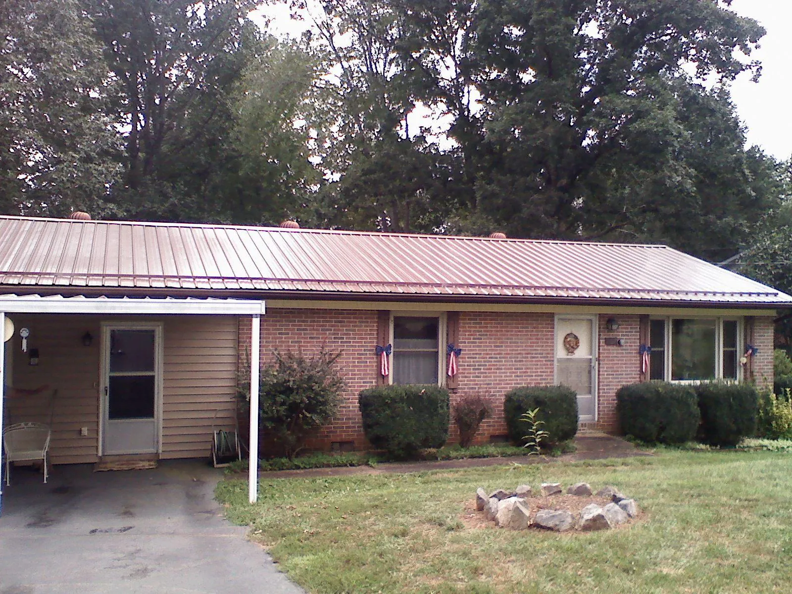 Bronze metal roof and carport on a brick ranch home — Roof Repair work by our crew in Dubois