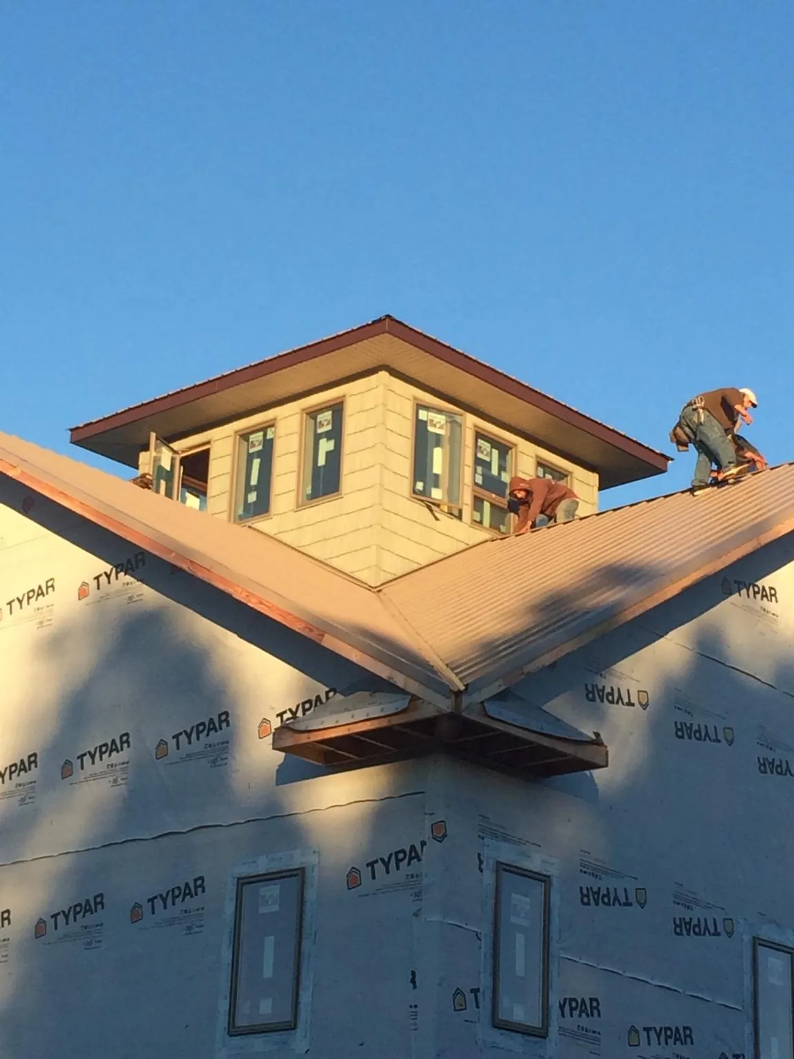 Roofers working around a rooftop cupola on a new metal roof at sunset — Roof Waterproofing in Dubois by Roofing Brothers